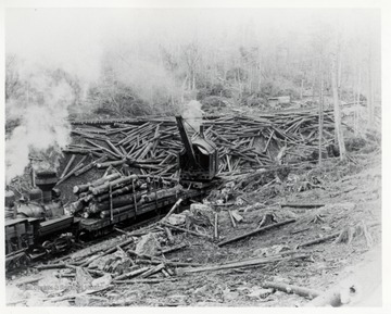 Crane loading logs on flatbed train car.  Workers securing logs.