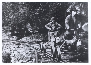 GC and E Leatherwood Creek branch; front:  Adam J. Hamrick; rear: Judd Wolfram, Webster Co. Extension Agent; note wall built to support railroad; note, also, sway in tracks just to rear of speeders.