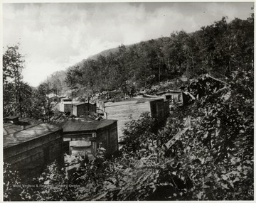 Small, wooden structures flank a hillside.