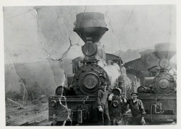 Two train engines and two men in front of them.  