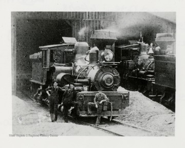 Three men in front of a train engine.  