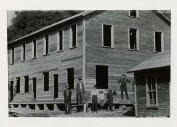 Men standing in front of an unfinished building.  