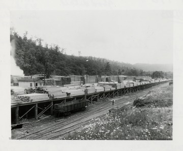 Lumber piles by a train track.  