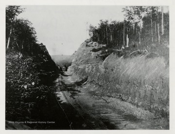 Tracks run along cut in hillside.  Train engine back in the distance.  