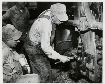 Walter Good applies wrench to the grease cups lubricating the side rods of his engine before going up on the Mt. while fireman, Paul Bradley looks on.  Both were veterans of log hauling days before passengers where hauled on Cass Scenic Railroad.  