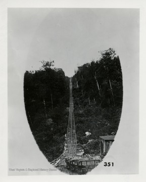 Train tracks going up a steep hill through the forest.  