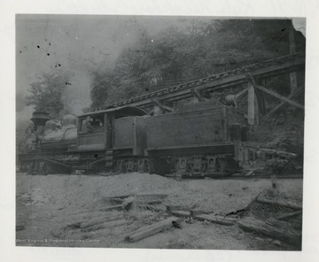 Side view of Shay train engine beside a trestle.  Original from C.B. Cromer