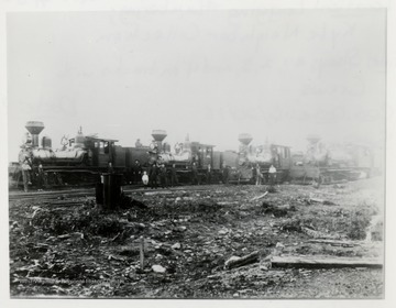 Train engines and crews line railroad tracks.