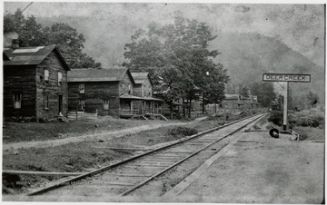 Deer Creek sign to the right, houses sit on the left side of the tracks.