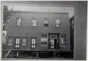 Two men standing at doorway in front of large building.