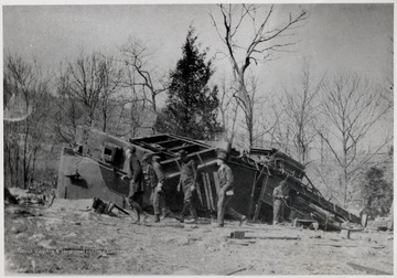 Men walking around the remains of a wrecked Shay train engine.