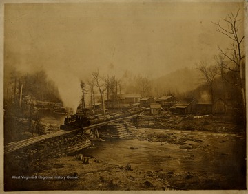 Shay locomotive and fully loaded log cars on a bridge over the Cherry River in Nicholas County, W. Va.