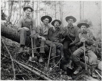 Five crew members sitting on a log.  The gentleman in the middle is John Swisher.