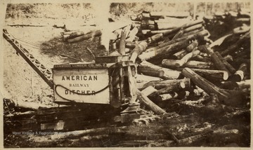 Equipment loads a large pile of logs.