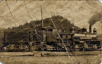 Four men standing in front of the side of a train engine.