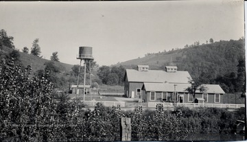 Two Buildings and a tower enclosed in a fenced area.