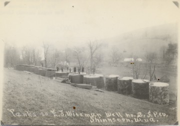 Men standing on top of a row of oil tanks in Shinnston, W.Va.