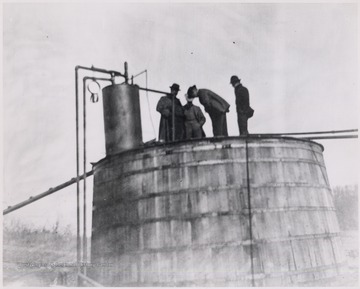 Men standing on top of an oil tank