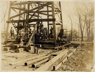 Men standing at the bottom of a wooden derrick.  Keen Wolf.  Bull Bayou.  