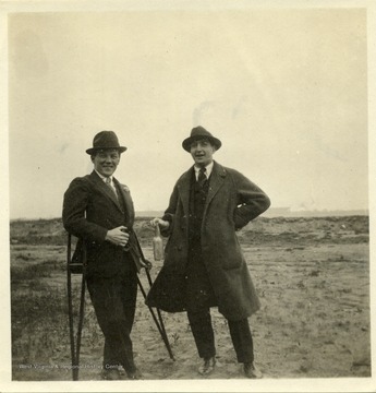 Captain Kelly, British Flying Corps, on crutches and Louis Bennett, Jr., West Virginia Flying Corps, holding bottle, pose for a portrait at Sheepshead Bay, May 24, 1917. 