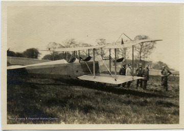 Group of men stand in front of an airplane.