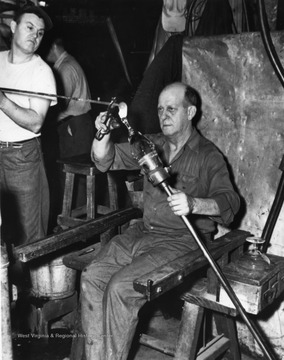 An unidentified Fostoria Co. worker on the job adding the base to a glass goblet.