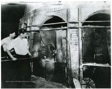 Men at work in the glass factory gathering glass from the ovens.