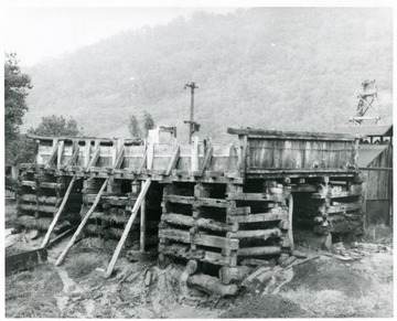 Well in right background. Foreground is storage tank for brine, the salt water cistern.  Brine from all wells is piped into this cistern which serves merely as a reserve supply should the wells be shut off for a short time.  The bottom logs were place ca. 1870.