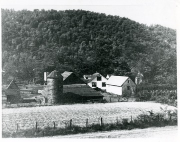 Salt works buildings in the background and a field in front.