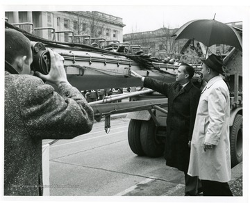 A photographer captures the moment when Governor Barron touches the U.S.S. West Virginia mast outside of the capitol building. 