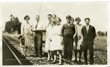 Group portrait of the Staff of the West Virginia Farm Institutea and Community Chautauqua Train from left to right: Miss Gladys Scranage, State Agent, W. Va. Un., H.B. Davis, Marketing Specialist, State Dept. of Agri., J.O. Knapp, State Agent, W. Va. Un., Miss Fern Carl, Home Industries Specialist, W. Va. Un., Wm. Benfield, State Club boy, Miss Frances Sutphin, State Club girl, Dwight Skaggs, State Club boy, Miss Mildred Gill, State Club girl, Mrs. E. G. Reed, chaperon, Waldo Craig, Plant Disease and Insect Specialist, State Dept. of Agri.