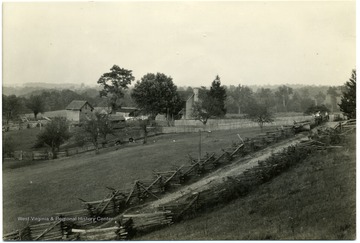 Picture of a house surrounded by fields. Text on back reads, 'So land [sic] as the existing buidings stand much of poorer land will remain in use.  Their replacement in the Dekalb stony loam and Dekalm stony silt loam land is ordinarily not an economical investment.' U.S. Department of Agriculture, Bureau of Agricultural Economies, Photographic Section number 18433.