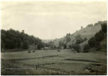 Looking up into a Narrow V-shaped valley with a house and acres of fields surrounding it. 