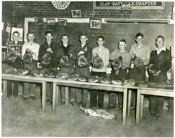 Group portrait of young boys holding up meat products.