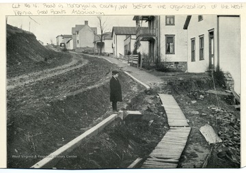 Picture of a boy standing next to the Cut No. 16 Road in Monongalia County, W. Va.  before the organization of the W. Va. Good Roads Association. See photograph number 001695 for a view after improvement.  From the Report of the W. Va. State Board of Agriculture for the Quarter Ending Sept. 30, 1908.