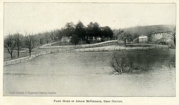 A fenced in field with a barn and farm houses in the background.