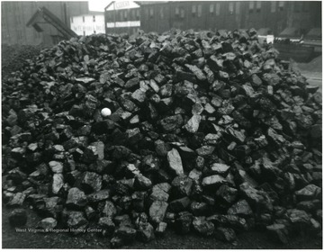 A pile of coal with large chunks sitting in the yard of a coal processing plant.