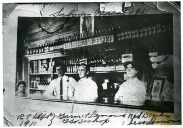 A child and three men stand behind the bar in this saloon. 