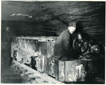 Caption reads, 'Good dependable motive power is just as necessary in a coal mine as on a railroad. This picture shows one of White Oaks ten ton electric locomotives used to haul loads and distribute empties in our mines. A Crew consists of a motorman and brakeman, or trip rider, who pull loads from the working places to convenient sidings where they are picked up by the main line locomotives, who haul to the tipple or shaft bottom. A large producing mine uses fifteen and twenty locomotives and five hundred mine oars in maintaining production.'