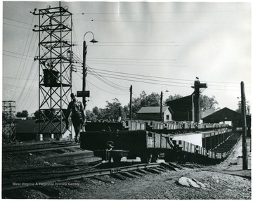 Miner walking next to coal carts outside of mine. 