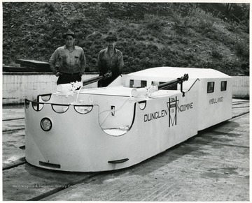 Two men stand in a mine ambulance equipped to haul injured to the outside.