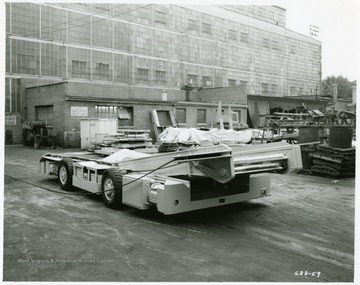 An electric shuttle car sits in a warehouse yard.