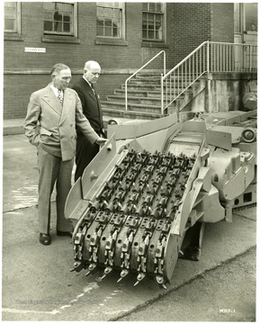 Joy executives stand beside a continuous mining machine.