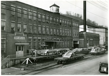 Coal loaders sit outside the Joy Manufacturing Factory.  Caption on photo reads, 'Mine equipment suppliers are busy turning out machinery for mechanical mining. For example, Joy Mfg. recently went on double shift operation to speed up production of mining machinery.'