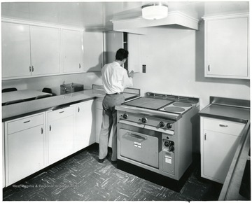 Unidentified man looks through the cupboards in the galley of the "Humphrey" towboat.