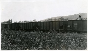 A man walking along top of coal cars.