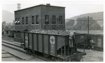 There is a man adjusting a crank on the coal car.