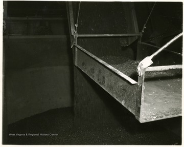 Coal dropping from a chute into a bin to be processed.