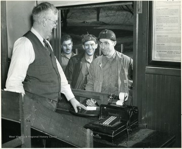 Photo shows W.A. Boggess, head clerk, hands Joe his two weeks pay envelope.