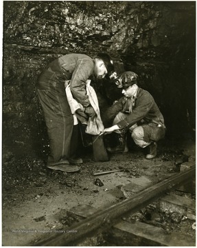 Two miners take samples of coal.